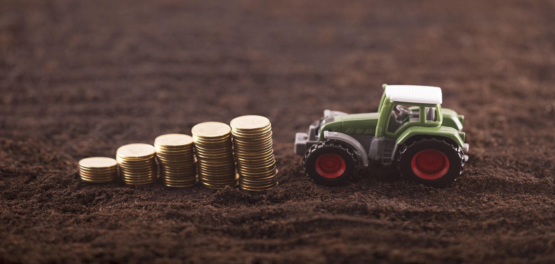 coins stacked next to toy tractor